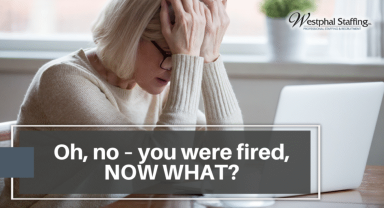 Older woman hunched over laptop with hands over her head to signal distress