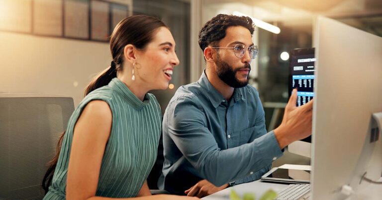 Two team members collaborating in front of computer screen