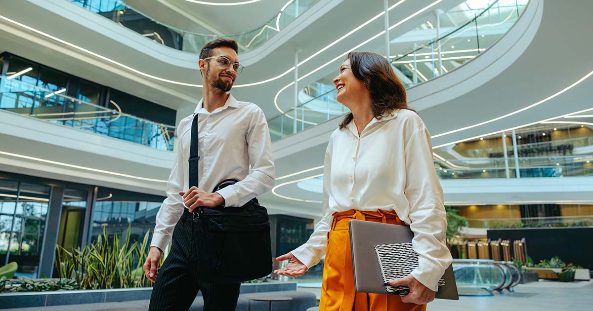 Two corporate professionals engage in a conversation about innovation and career growth in a contemporary office setting