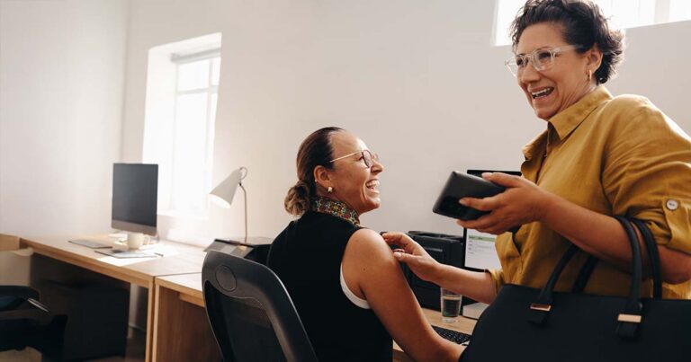 Two coworkers share a joyful moment while working together in a contemporary office environment,