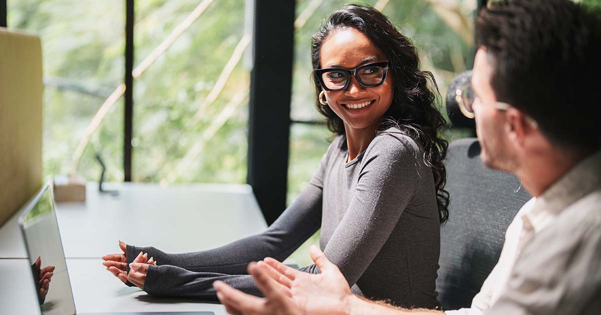 Male and female worker collaborating in a bright, modern office with window overlooking lush greenery