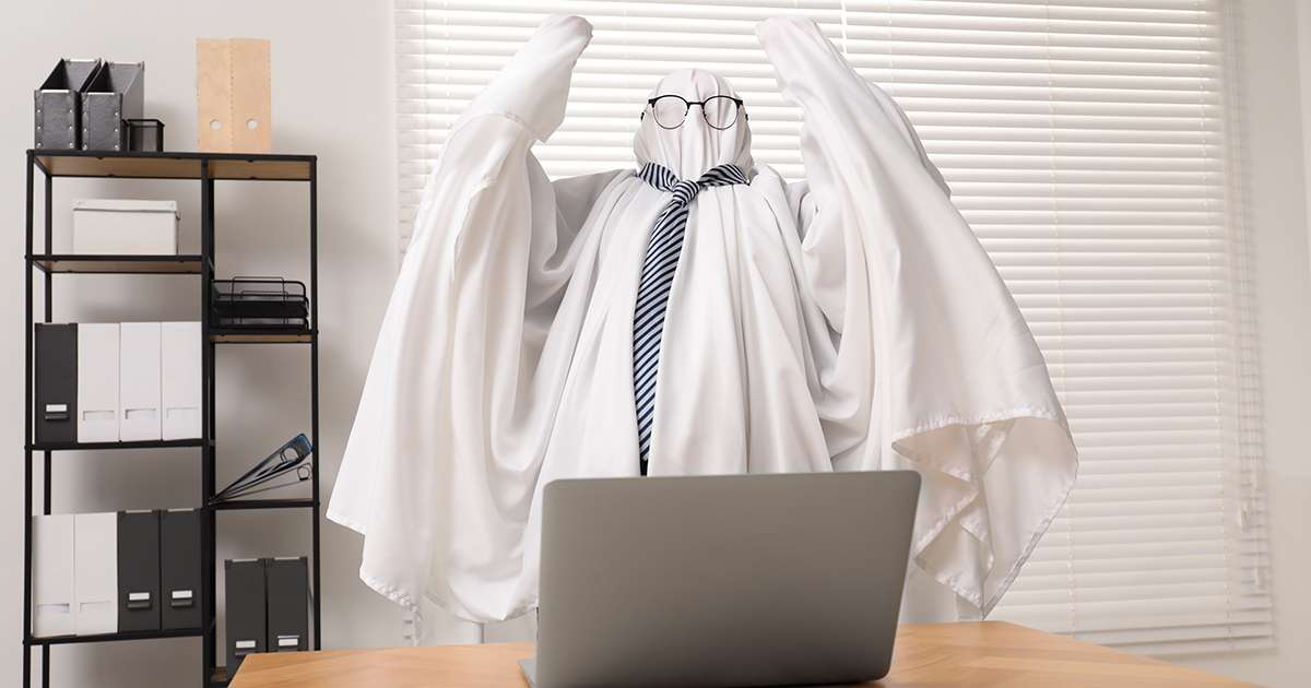 Ghost lifting his arms up in despair in front of a laptop