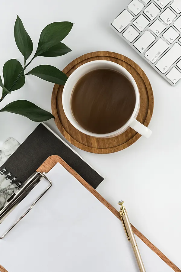 Top view of an office with notebooks, coffee mugs and keyboard