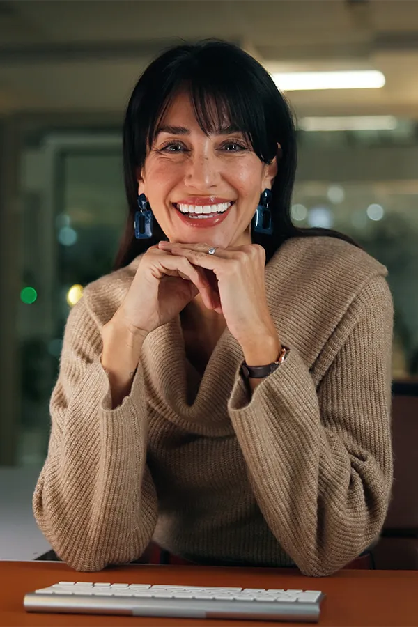 Woman resting elbows on desk while her hands touch her chin